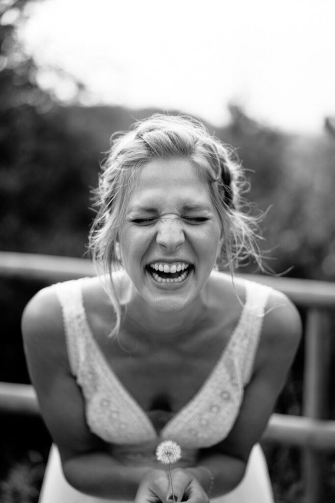 Bride holding her bouquet close to her face, smiling.